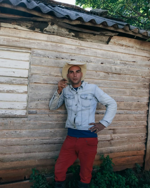 a man in cowboy hat holding up a cigarette