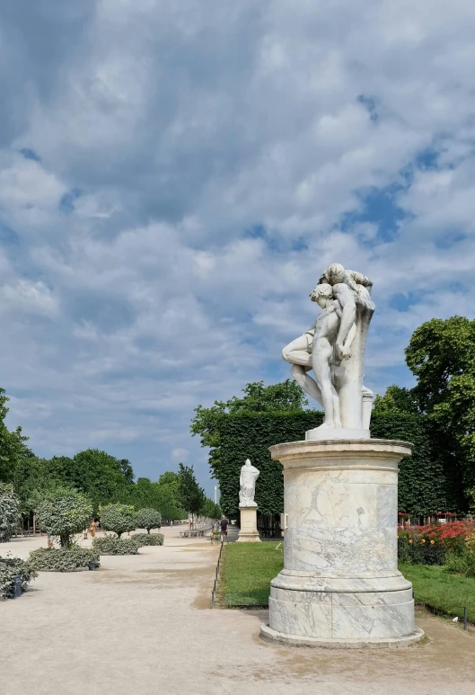 a statue is sitting on top of the sidewalk in a park