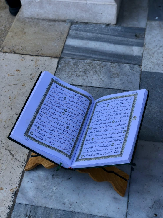 a open book on the ground with a wooden stand