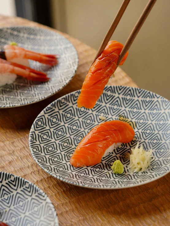 chopsticks being used to take sushi from plate