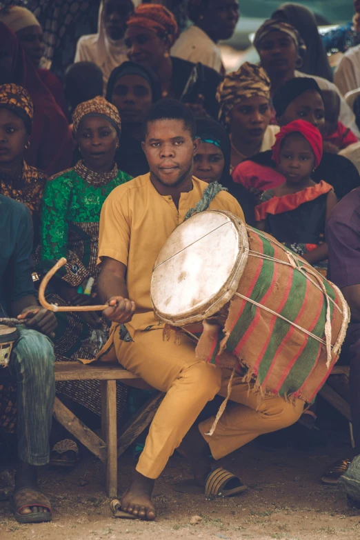 a man with drum and people sitting around him