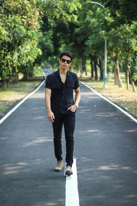 a man is standing in the middle of a tree - lined road