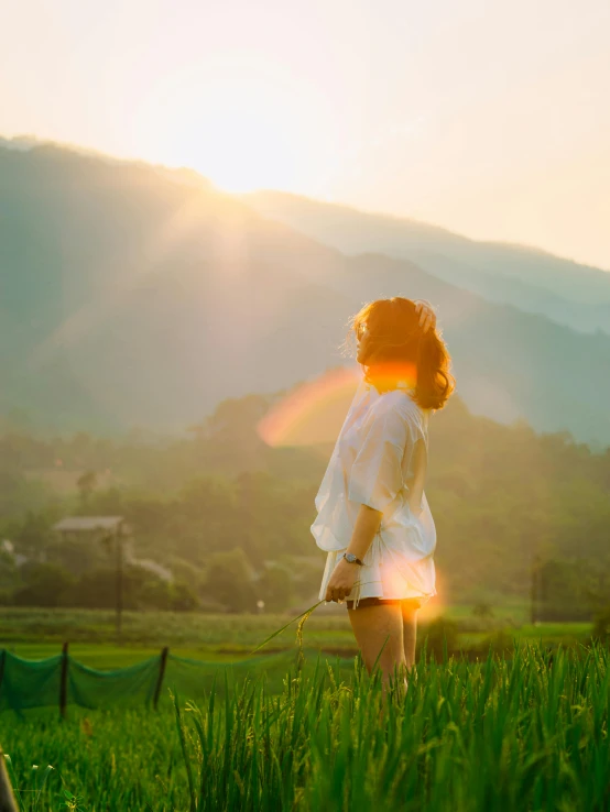 a person in white holding a dog with sun shining over the valley