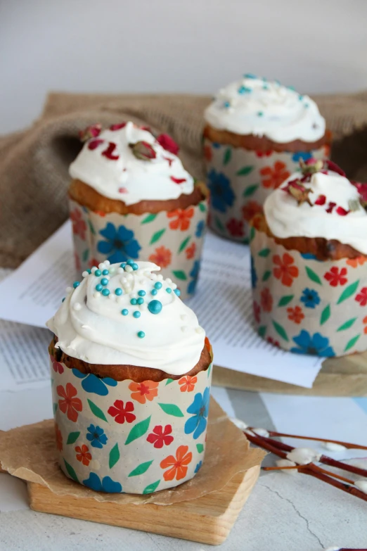 four colorful cup cakes with frosting and sprinkles