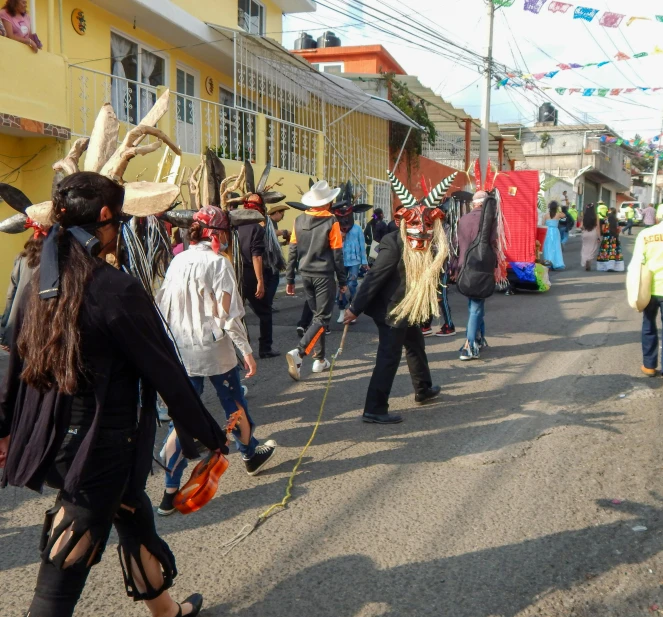 the crowd in carnival costumes are marching through a street