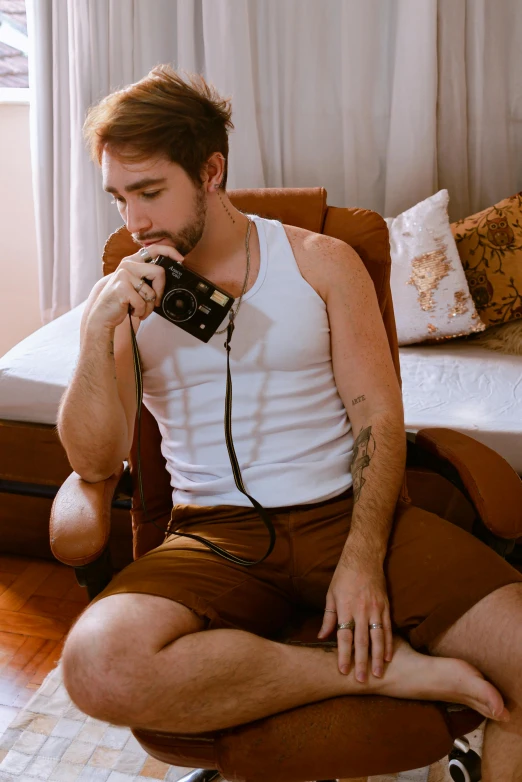 a man sitting on a brown chair with his foot up to his mouth