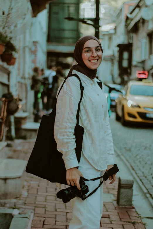 a woman standing on the side walk holding onto her camera