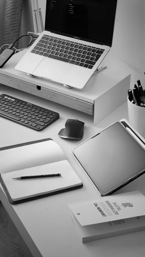 a desk with a laptop, notebook and books on it