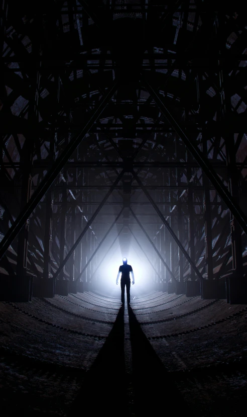 a lone person standing in the middle of a dark tunnel