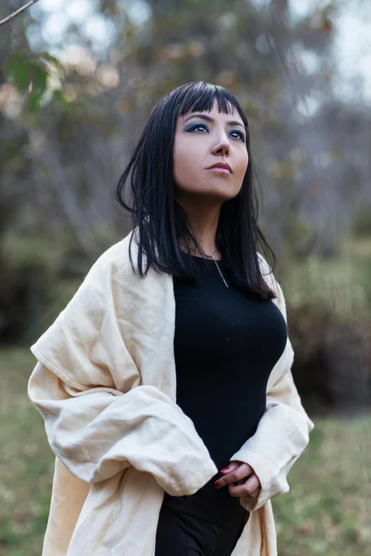 a woman with black hair in a black top and white jacket