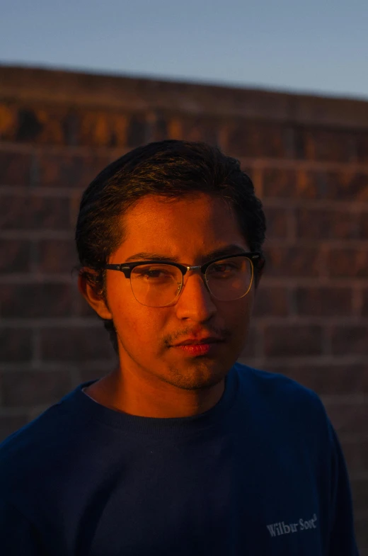 young man in dark shirt standing outside with brick wall