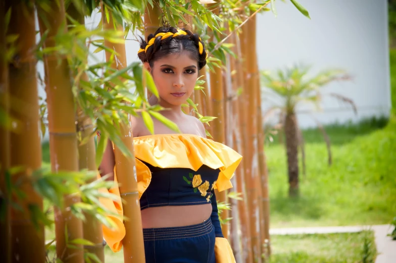 a girl with bright colored makeup and blue shorts is standing by bamboo trees