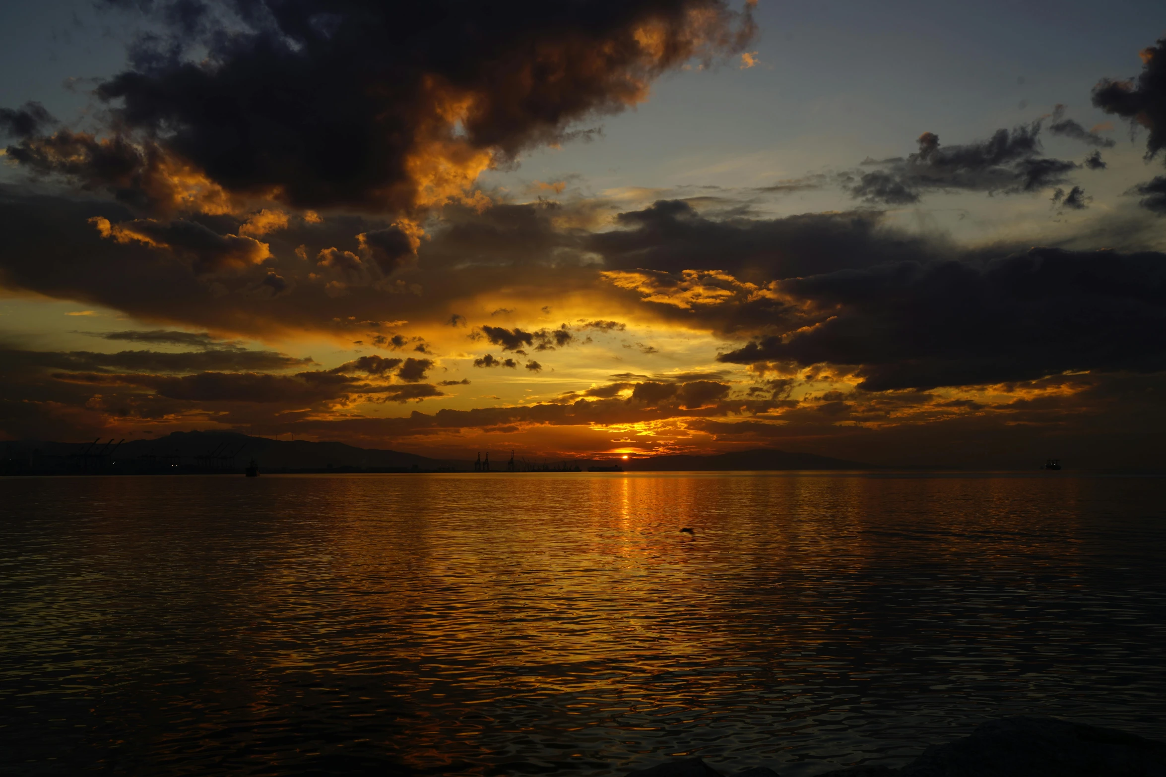 a sky filled with clouds and the sun reflecting off the water