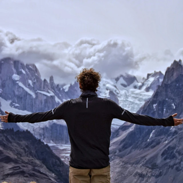 the man in the black jacket is watching the mountains