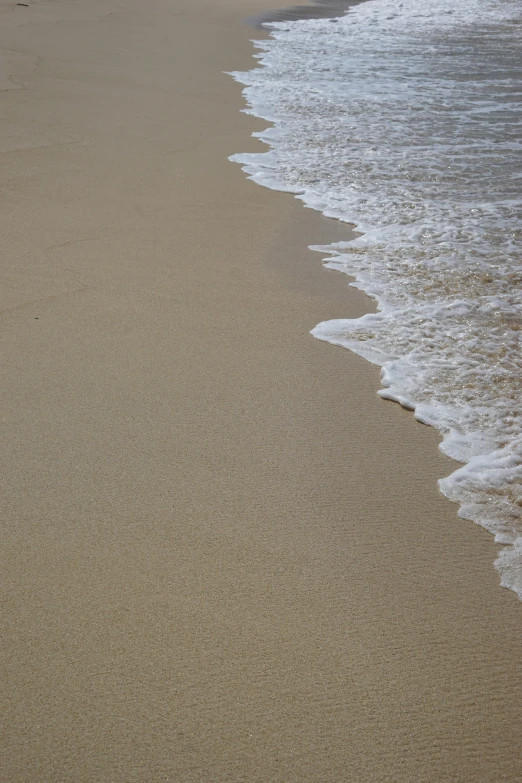 a sandy beach with white capped waves coming into the shore