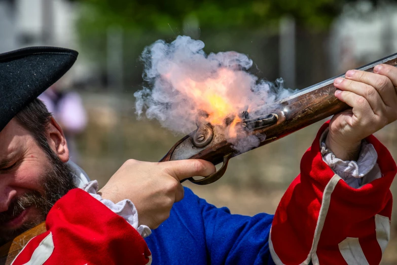 a man is holding up a gun that has flames coming out