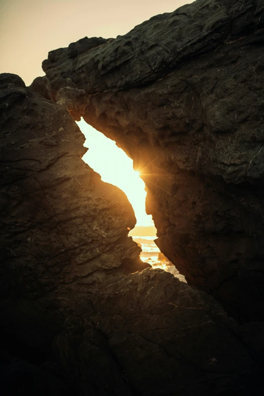 the sun is rising through a window in a rock formation