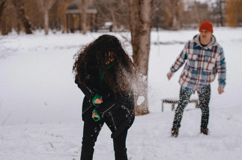 the young man and woman are walking through the snow