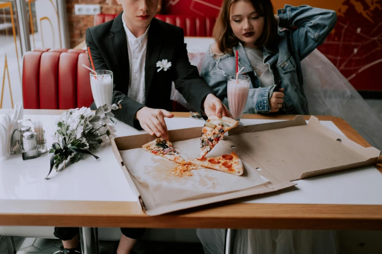 a woman eating a slice of pizza near two guys