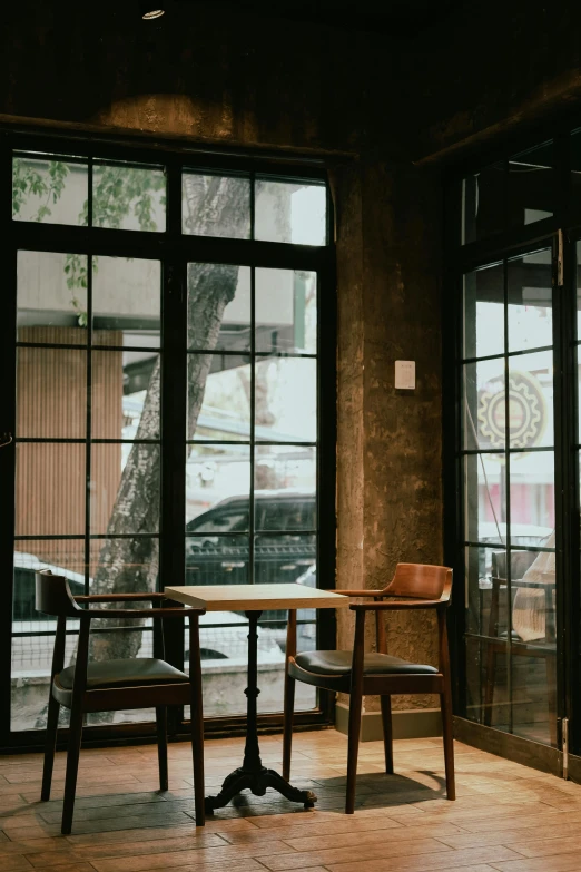 the room has two chairs, an empty table and two open windows