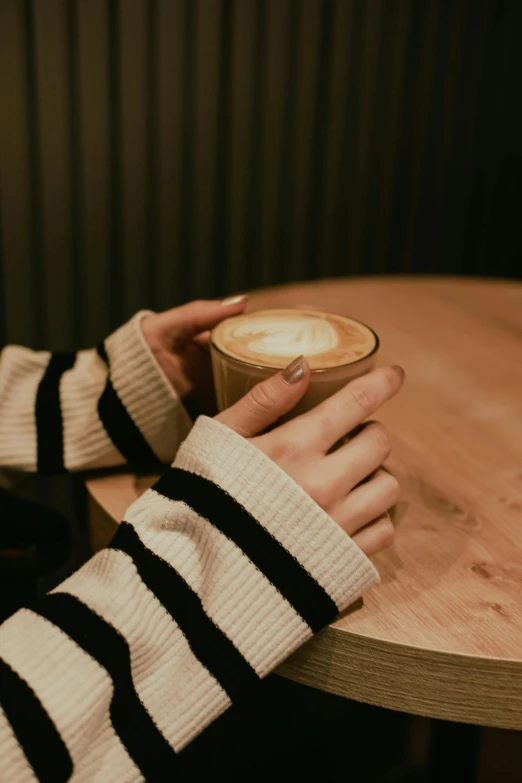 a person holding a cup of coffee at a table