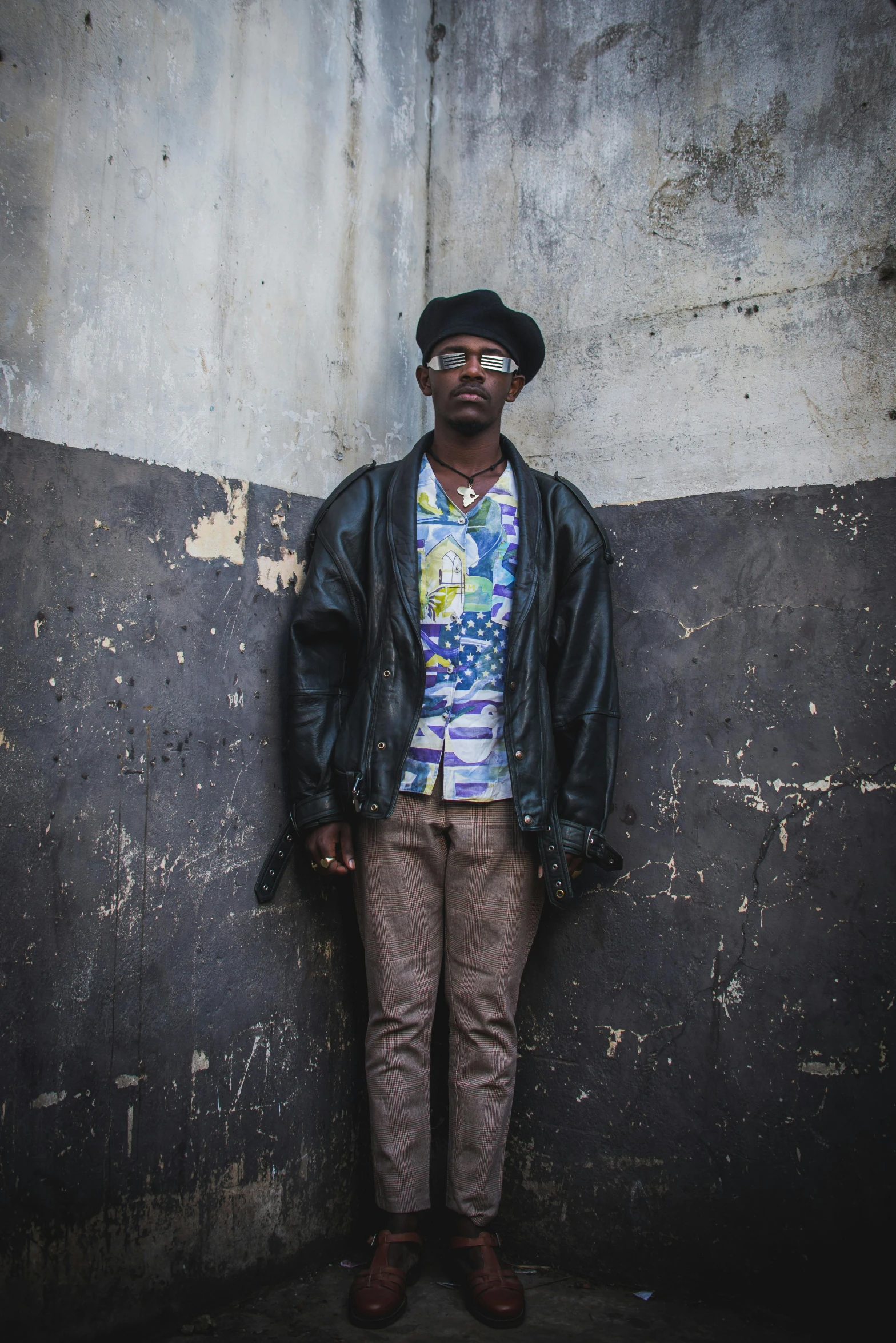 a man with a hat standing in front of a wall