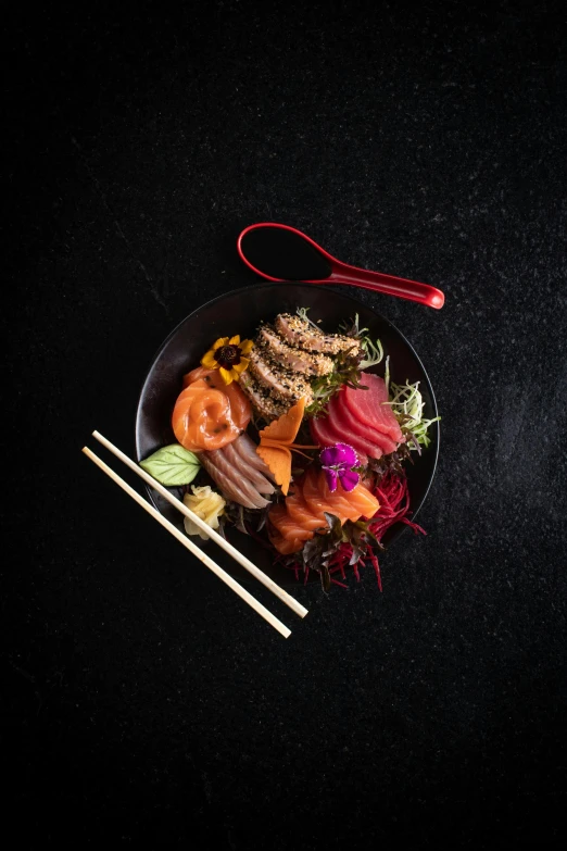 a bowl with sushi is on the table next to chop sticks