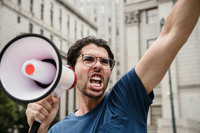 a man in sunglasses is screaming and holding a megaphone