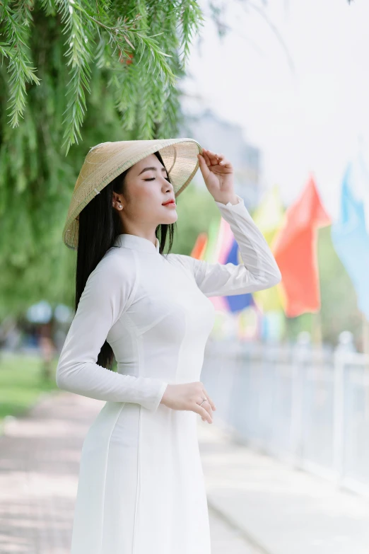 a woman posing in white is wearing a straw hat