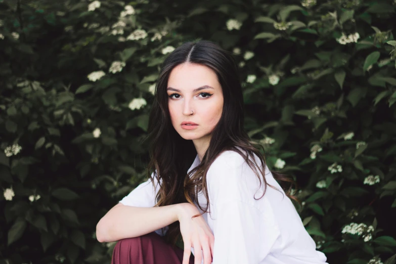 the girl is sitting on a bench by a tree