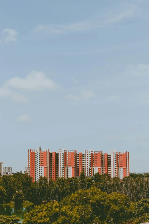 an orange and white apartment building behind trees