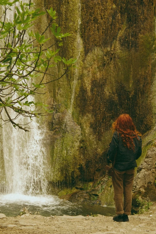 a person standing in front of a small waterfall