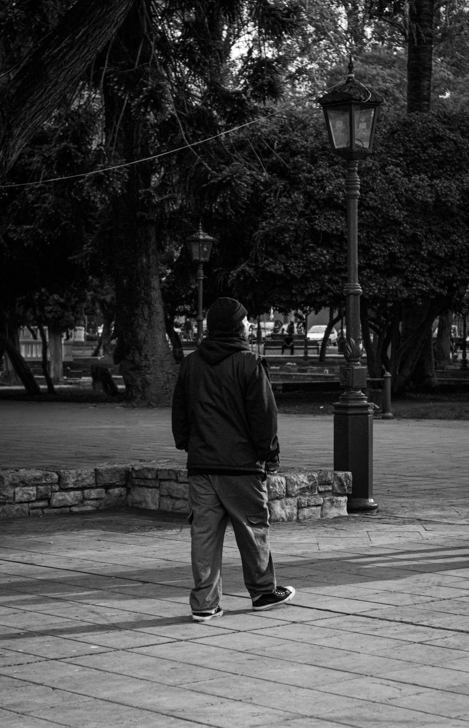 a man walking on the side walk of the road in black and white