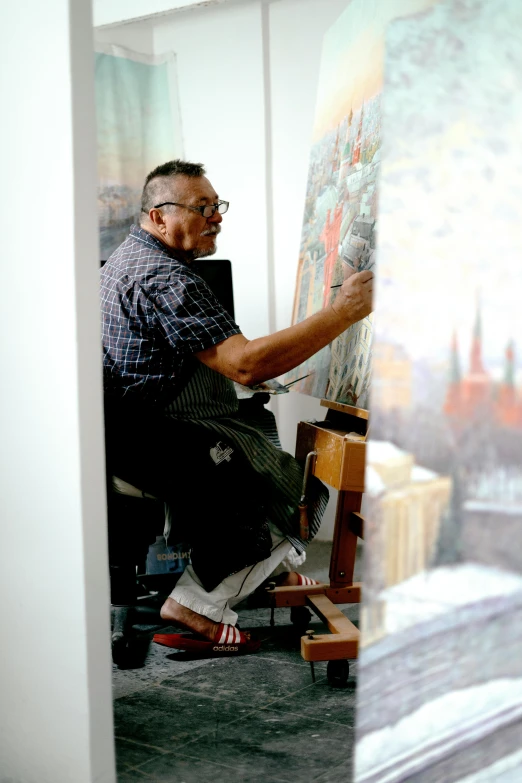 the man is painting on an easel in his studio