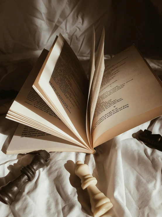 two open books on a bed next to a hammer