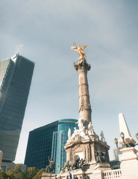 an angel statue on the corner of a building and tall skyscrs