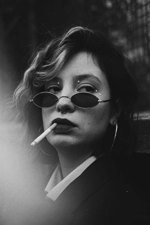 a woman in sunglasses smoking soing and looking away from the camera