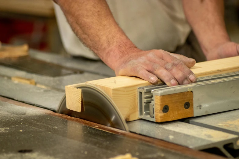 a woodworking person uses a bench saw to cut some boards