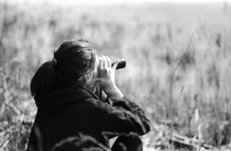 a woman is taking a po while sitting in a field