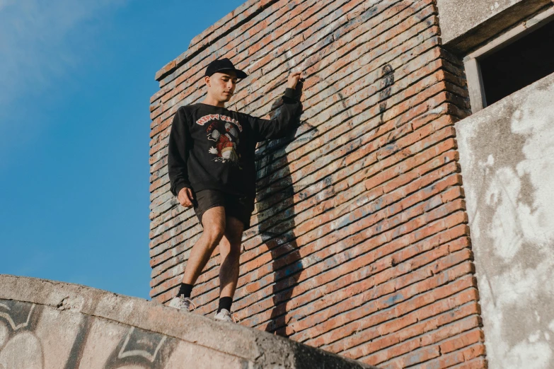 a young man is hanging off of a brick building