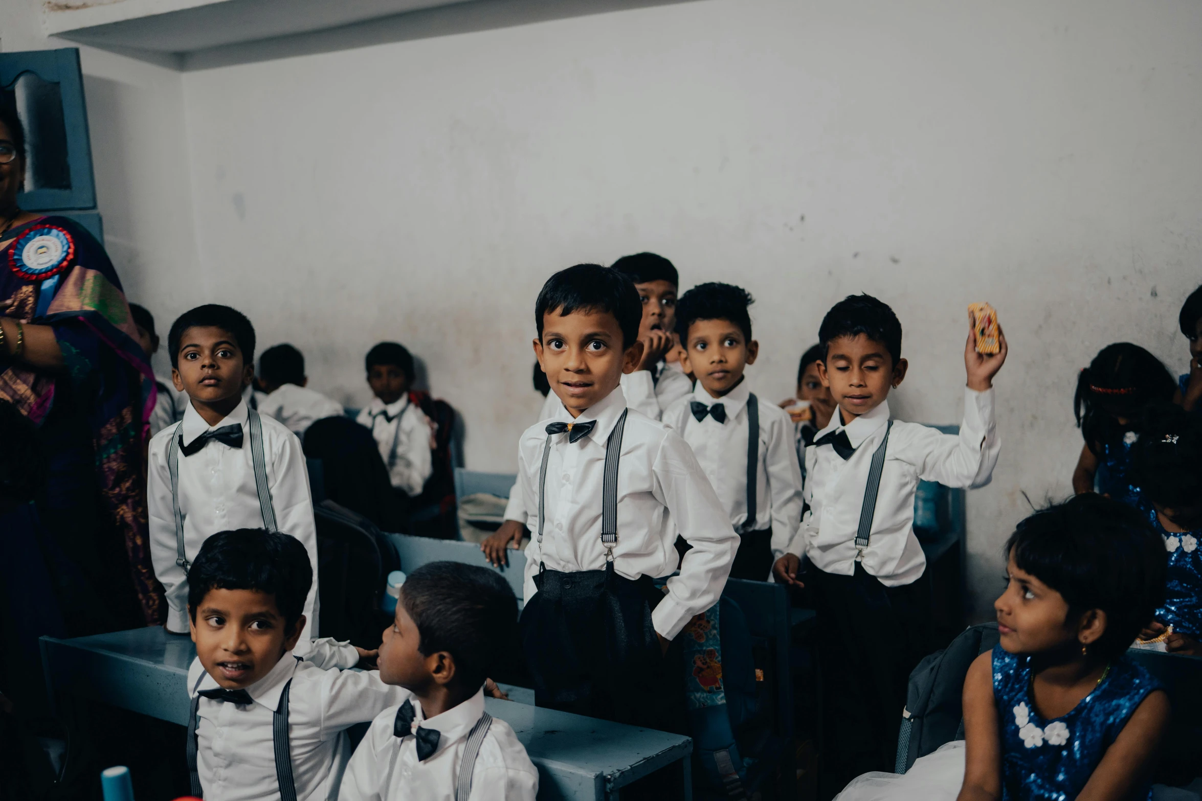 children in dress clothes are wearing ties and sitting in chairs