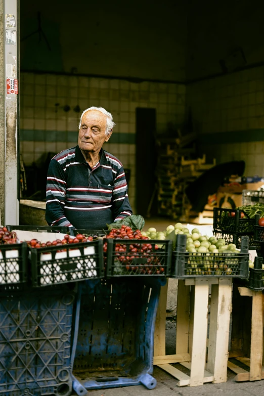 a man is standing by some crates at an outdoor market