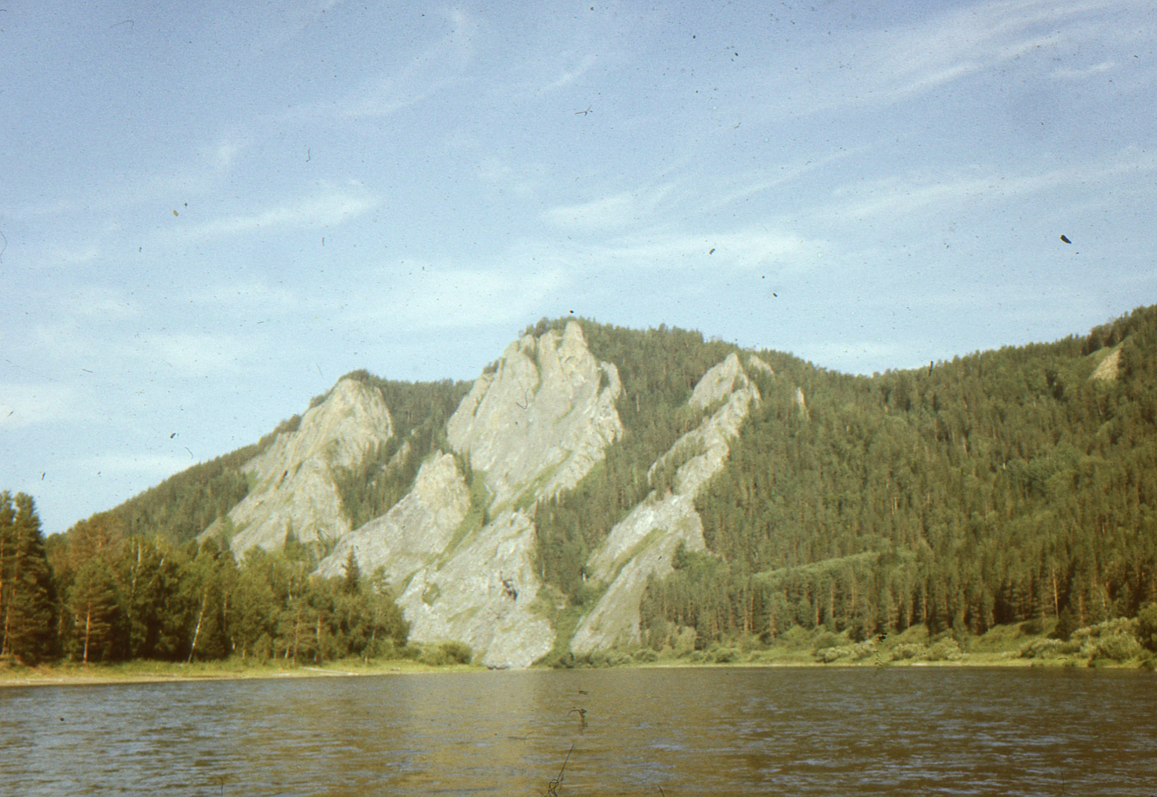 mountains stand tall on the shore as trees reflect in the water