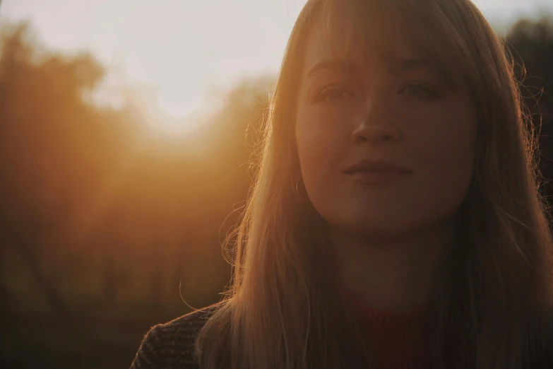 a woman's face is obscured by the sun behind her