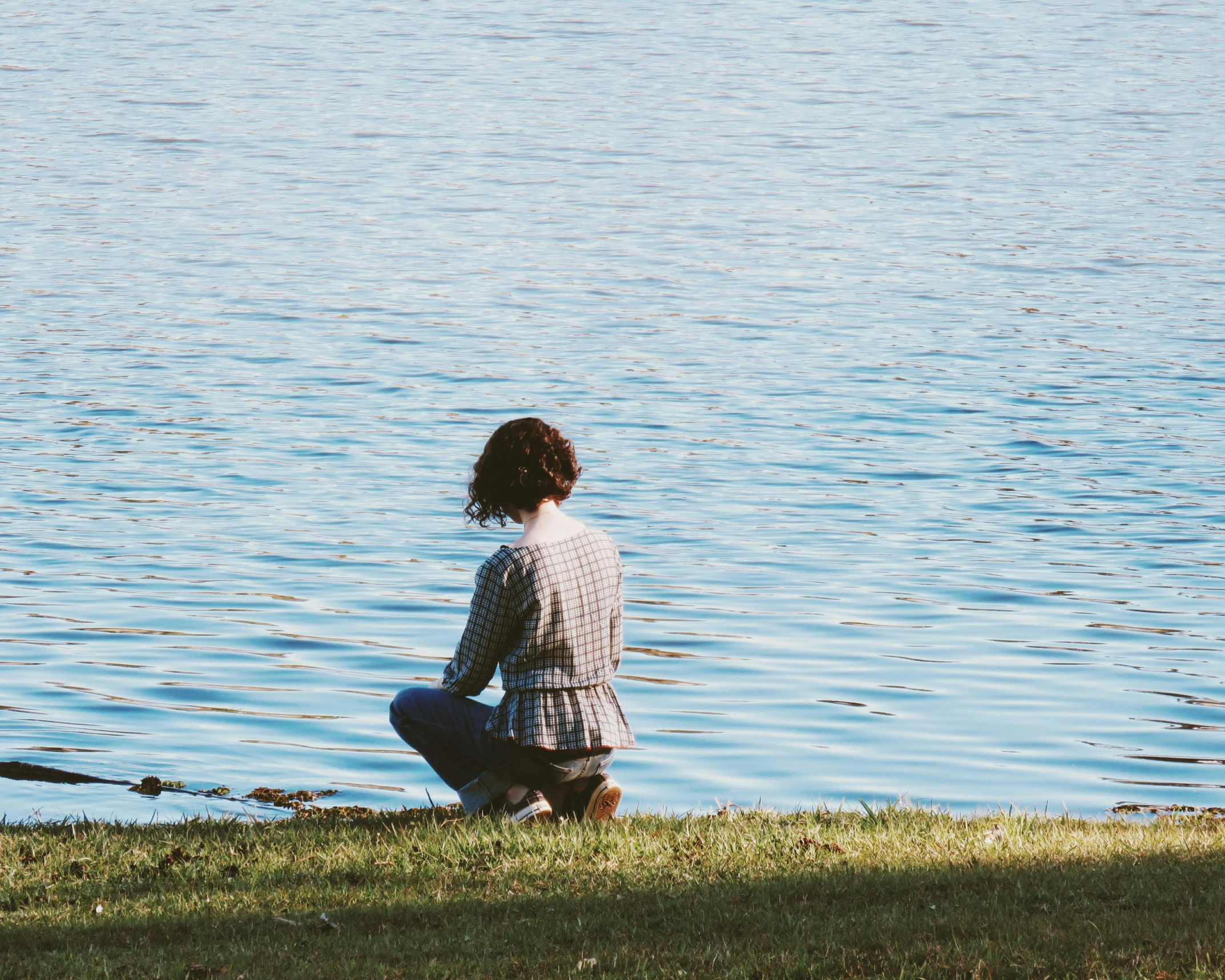 a woman sits near the edge of the water