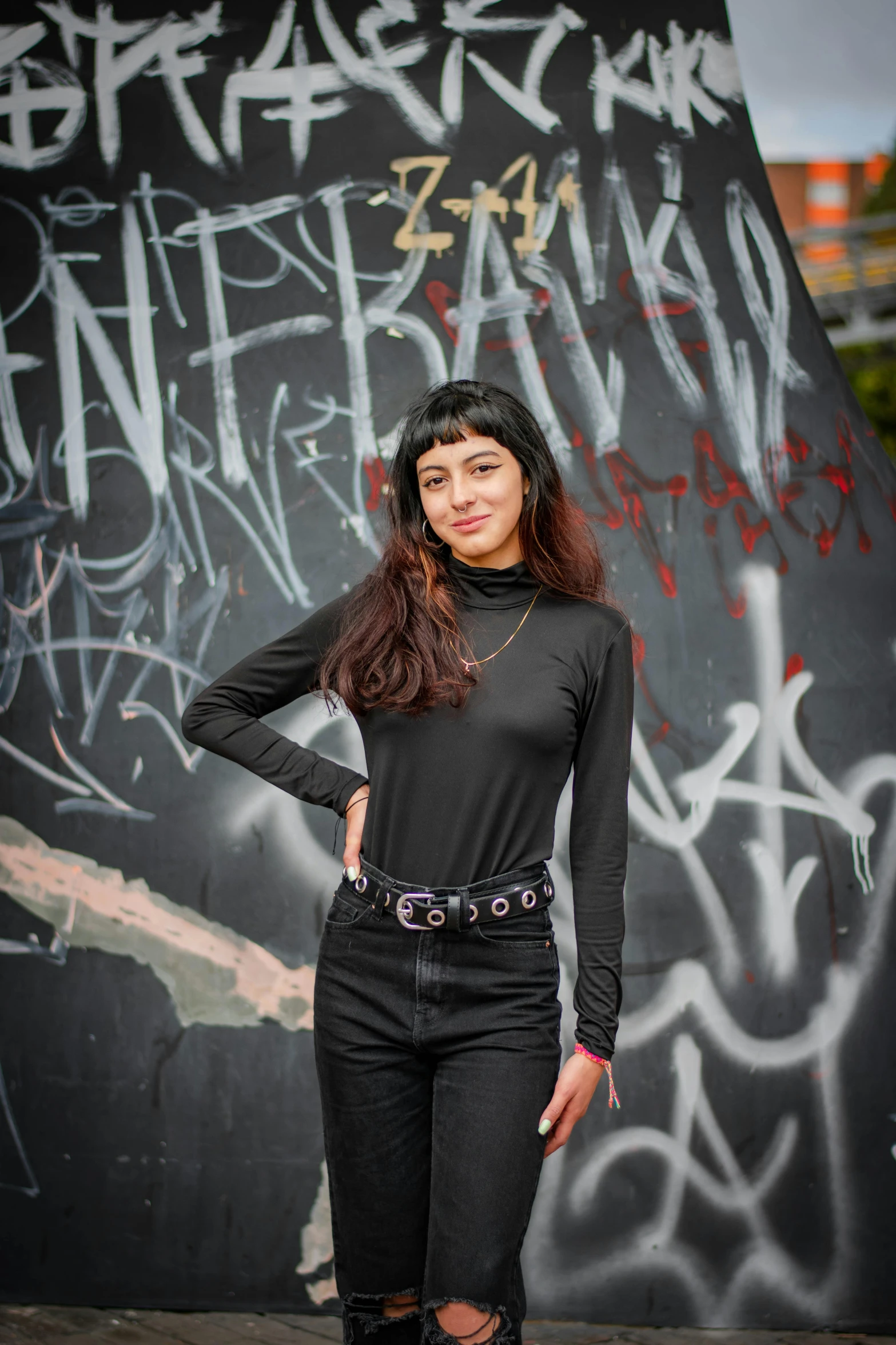 a woman standing next to a wall with graffiti