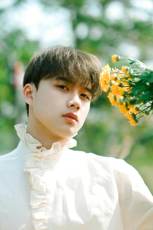 a boy wearing a shirt and holding a plant with yellow flowers