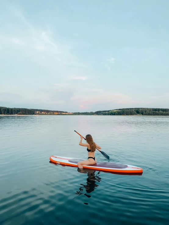 a woman with a paddle on her stomach paddling on a paddle boat in the ocean