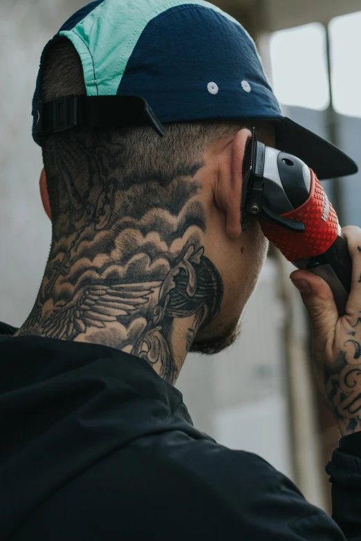 a man with tattoos holds a cell phone to his ear