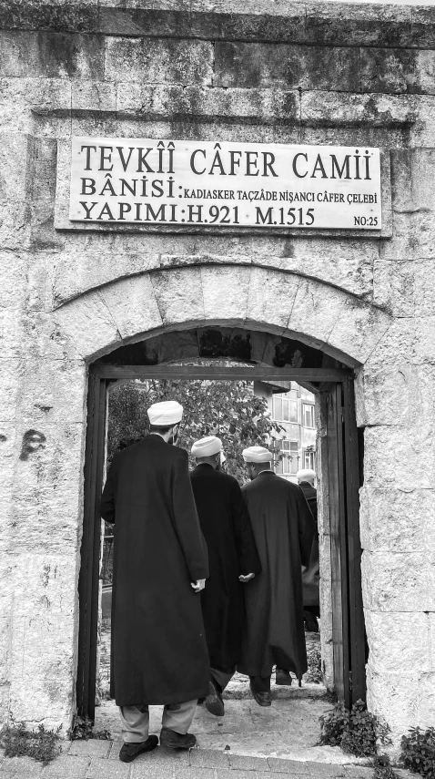 two men wearing black robes stand in front of a building